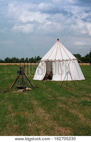 White Tent and Wooden Tripod for Bonfire on Meadow