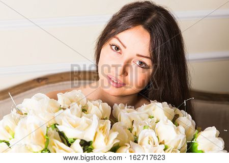 portrait of a beautiful brunette girl with a bouquet of roses.