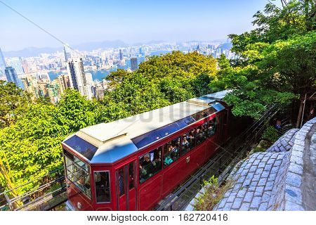 Hong Kong, China - December 10, 2016: The popular red Peak Tram as he arrives at the terminus of Victoria Peak, the highest peak of Hong Kong island, with panoramic city skyline background. Sunny day.