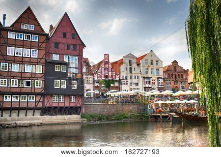 LUNEBURG GERMANY - November 23 2014: Historic old city and old harbour of Luneburg at evening with houses water cafe umbrellas and boat