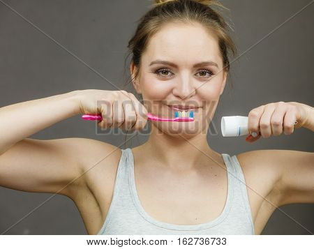 Woman holding brush and tooth paste for teeth cleaning. Happy funny smiling girl with toothbrush. Oral hygiene.
