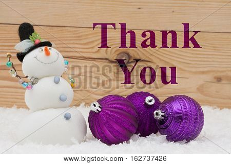 Thank you message Some snow Christmas ornaments and a snowman on weathered wood with text Thank You