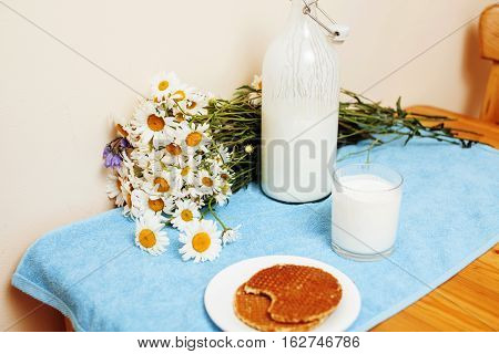 Simply stylish wooden kitchen with bottle of milk and glass on table, summer flowers camomile, healthy foog moring concept noone close up