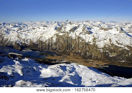 amazing scenic view of snow mountains and frozen lake in Switzerland Europe on a cold sunny day with blue sky at Saint Moritz Corvatsch peak in Engadin in winter vacation and holiday concept