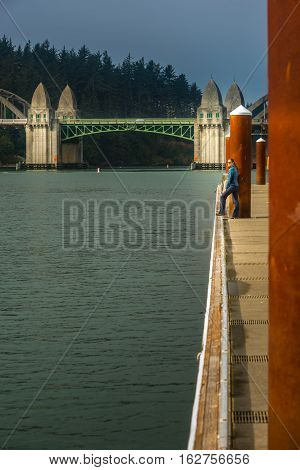 Tourist Looking At Siuslaw River From The Florence Marina Oregon