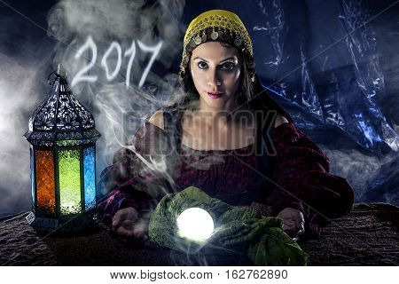 Female fortune teller doing a psychic reading with a cystal ball predicting the future of 2017. The image is an illustrative editorial of the new year.