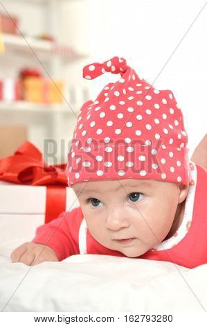 Adorable baby girl in red clothes with gifts