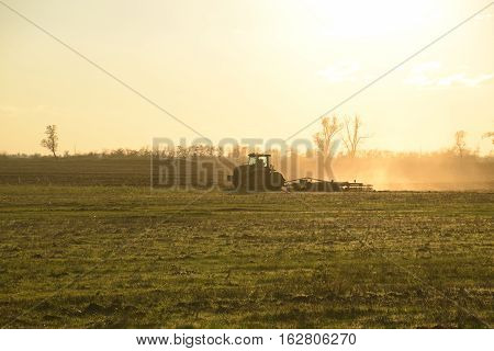 Tractor At Sunset Plow Plow A Field. Tilling The Soil In The Fall After Harvest. The End Of The Seas