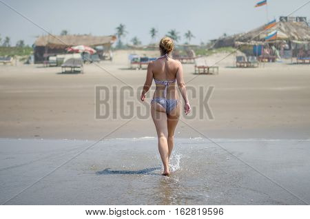 curvy blonde girl in a swimsuit comes out of the water