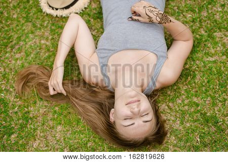 Blonde girl with long hair lies on green grass