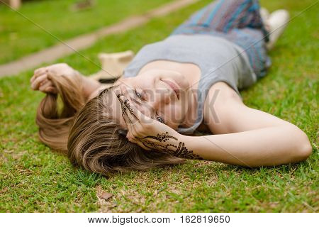 Blonde girl with long hair lies on green grass