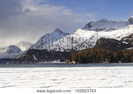 amazing landscape scenic view of Engadin valley in Switzerland Sils Maria village with snow on Alp mountains and frozen lake on a cold sunny winter day in tourism and holiday destination