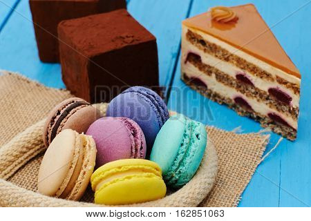 Sweet piece of pie, chocolate cake and macaron on wooden table