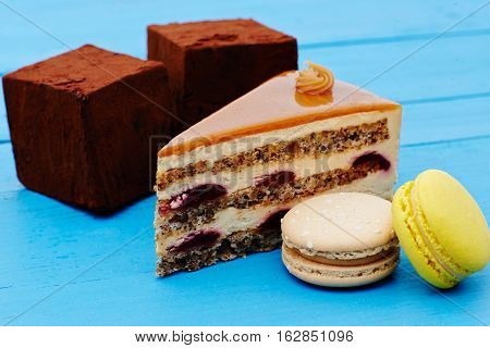 Sweet piece of pie, chocolate cake and macaron on wooden table