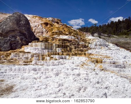 Red and white travertine terrace calcium carbonate deposits blue sky at Mammoth Hot Springs Yellowstone National Park