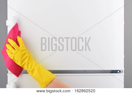 Hand In Yellow Glove Cleaning White Refrigerator With Pink Rag