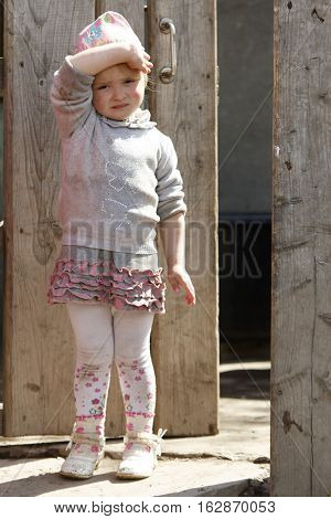 STINKA UKRAINE - APRIL 14 2016 - funny little girl stands in a wicket and covers by hand on April 14 2016 in Stinka village.