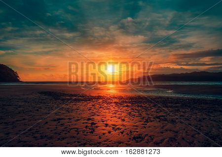 Sunset on the beach. View of the Sun and the mountains.