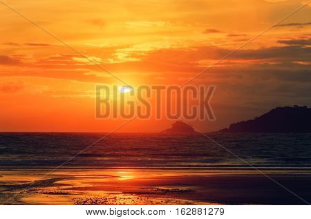 Sunset on the beach. View of the Sun and the mountains.