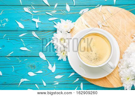 Still life with cup of coffee and flowers on light wooden table
