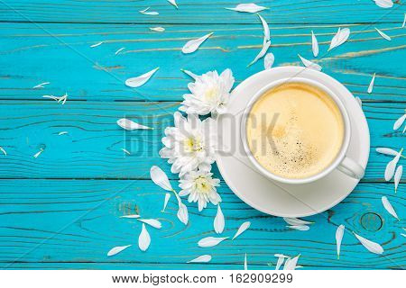 Still life with cup of coffee and flowers on light wooden table