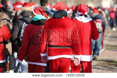 People With Red Santa Claus Clothes Walking In The Public Park O
