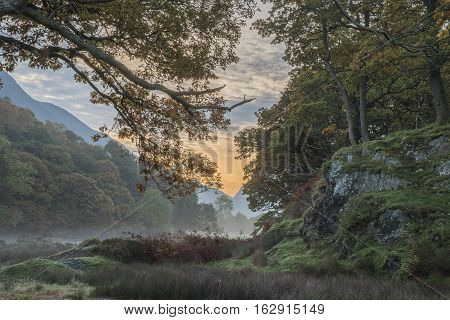 Beautiful Foggy Misty Autumn Sunrise Over Countryside Surrounding Crummock Water In Lake District In