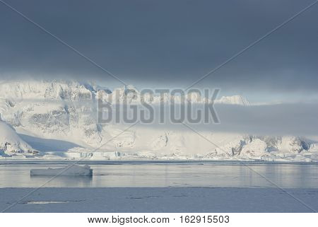 mountains of the Antarctic Peninsula covered with stratus clouds and icebergs Coast downtrodden