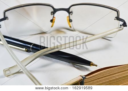 Closeup of the first blank page of old book with pen and glasses