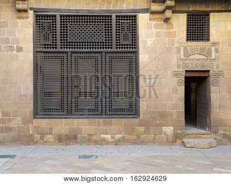 Facade (Mashrabiya window and open wooden door on stone wall) of Beit (house) El Harrawi an old Mamluk era historic house in Medieval Cairo Egypt built in the eighteenths century