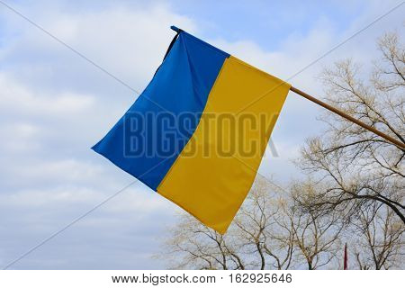 Flag of Ukraine with a black mourning ribbon. Flag on the sky background.