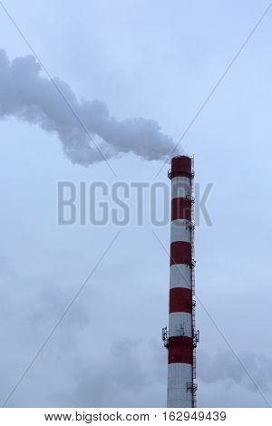 high pipe CHP on the background of blue sky fog smog and out clouds of thick smoke pipe red-and-white it's cold outside