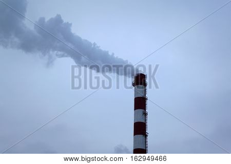 high pipe CHP on the background of blue sky fog smog and out clouds of thick smoke pipe red-and-white it's cold outside