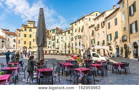 Lucca Italy - Oct 6 2016. In the center square of Lucca Italy. Early morning visitors started tour before restaurant set up.