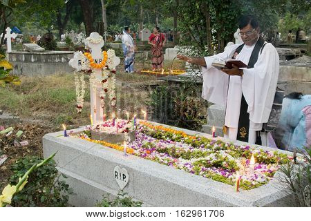 KOLKATA WEST BENGAL INDIA - NOVEMBER 2ND 2014 : Priest and relatives at "All souls day" remembrance at old cemetary at south Park Street Kolkata.