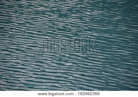 the water surface of a lake or river, river water surface texture, The blue surface of an alpine lake with light waves.