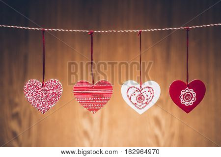 Colorful heart hanging on the clothesline on wooden background.