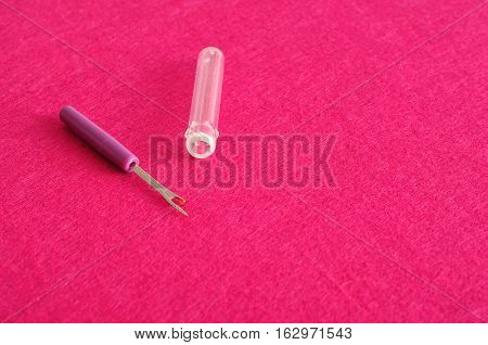 A purple stitch unpicker isolated on a pink background