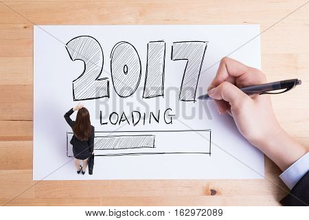 Business people writing 2017 new year loading text on the paper and woman look somewhere