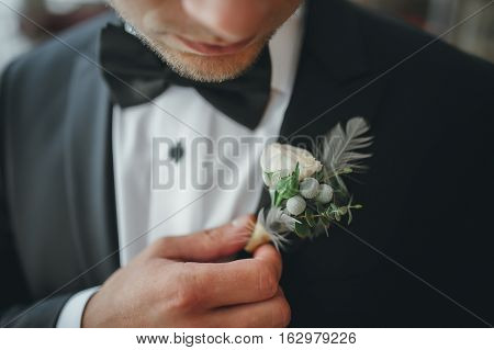 young groom boutonniere in his hand closeup