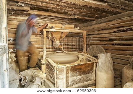 Man working in a small mill. Man making corn flour. Wooden water mill interior. Long exposure.