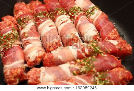 Chevapchichi meat in bacon roasting in a pan. Photo with bokeh effect.