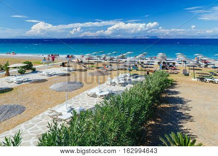 White wooden walkway on beach including umbrellas with deck chairs. Aegean Sea. Greece Rhodes.