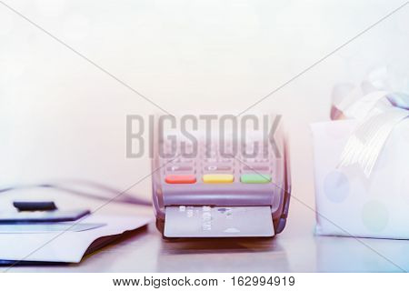 Credit card and card reader machine, on table with gift box background