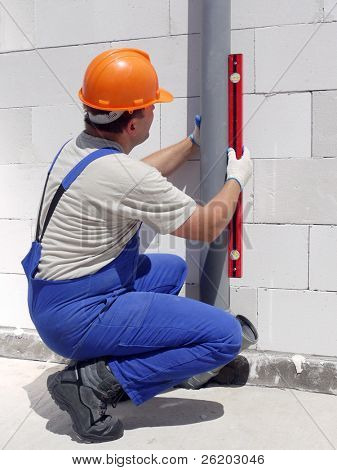 Instalatér pomocí úroveň pro kontrolu olovnicí sestavený pvc kanalizačních trub nedokončený domu
