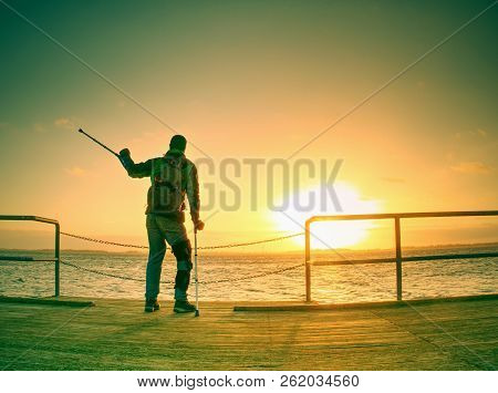 Traveler With Backpack Walk Dificult With Medicine Poles.  Young Tourist On Bridge  Near Sea At The 