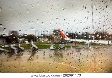 Water Drop On Mirror Window Of Airplane In Rainy Day While Landing At Airport With Blur Aircraft Out
