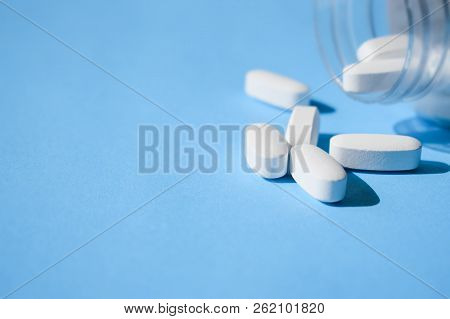 Oxycodone Pills. Opioid Pain Medication, Narcotic. Close Up White Pills With A Bottle On A Blue Back
