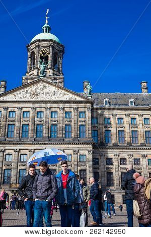 Amsterdam, Netherlands - March, 2018: Tourists At The Royal Palace Of Amsterdam Located At Dam Squar