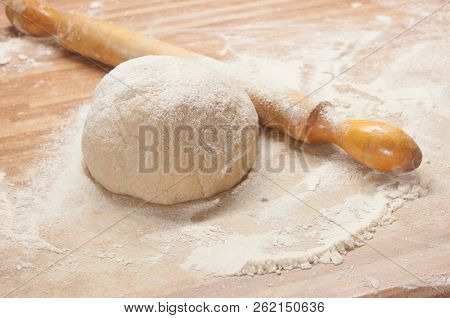 yeasty dough and rolling pin on wooden surface